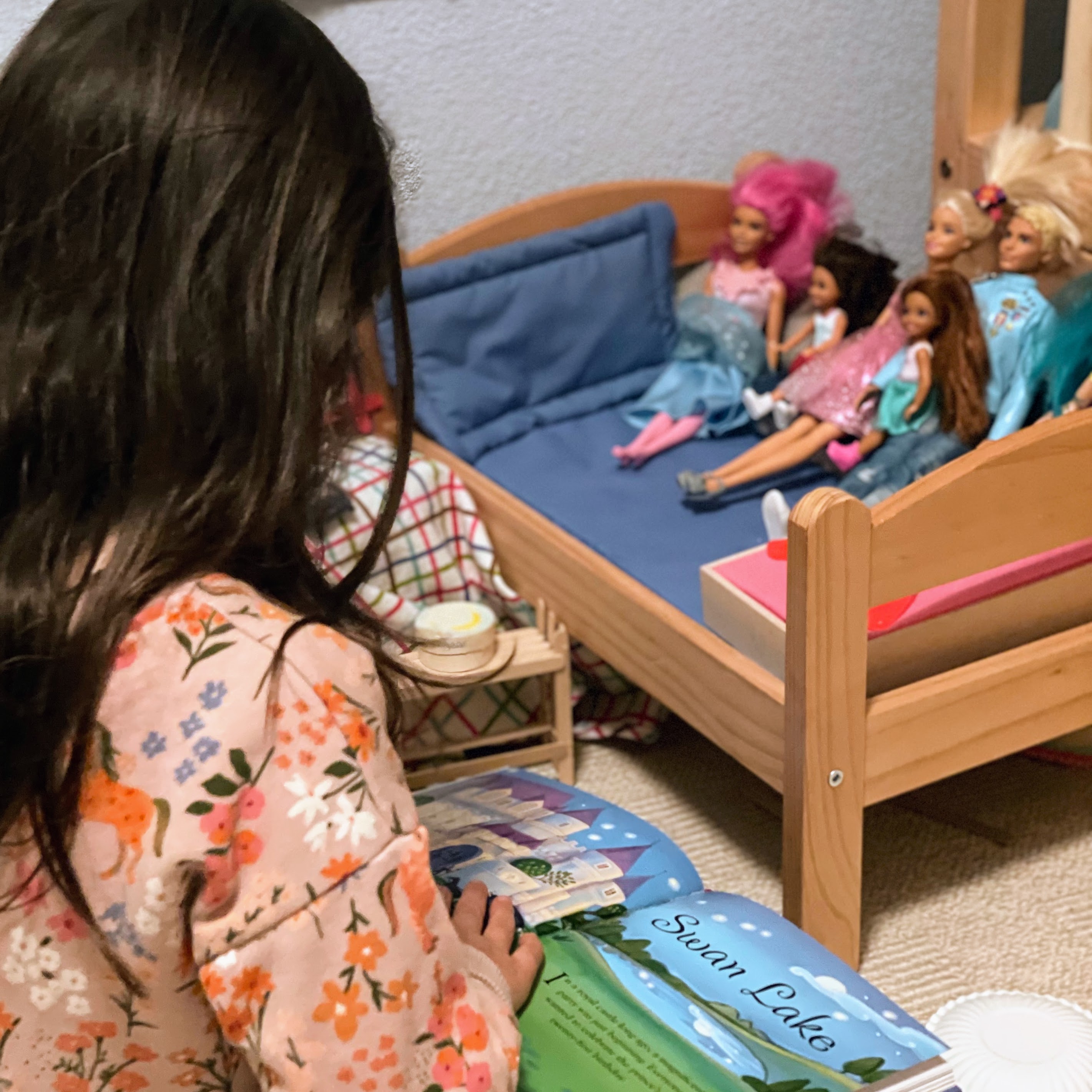 a girl reading a book to her dolls